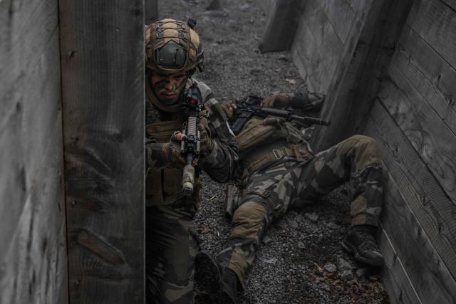 French Foreign Legion paratroopers from the 2nd Foreign Parachute Regiment (2e REP) take part in a trench combat exercise, one holding position inside the trench network while another lies on the ground after being declared a casualty, during exercise LIBECCIU 2026, in La Courtine, central France, on May 13, 2026. More than 700 légionnaires are deployed across two French regions for the ten-day field exercise, sharpening the night-warfare and rapid-redeployment skills that define the Legion's airborne identity. (Photo by Philippe LOPEZ / AFP)