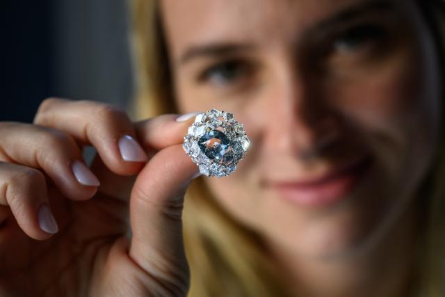 (FILES) A Christie’s member of staff shows a triangular-shaped fancy vivid blue-green diamond weighing 5.50 carats, known as "The Ocean Dream", during a press preview at Christie’s auction house in Geneva, on May 7, 2026. A vivid blue-green diamond of 5.50 carats, the largest known to date, was sold for more than $17 million on Wednesday in Geneva, exceeding expectations, Christie's announced. (Photo by Fabrice COFFRINI / AFP)