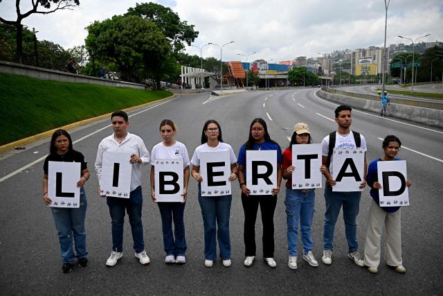 Students and relatives of political prisoners hold signs whose letters spell out the word in Spanish, "Freedom," as they take part in a protest calling for their release outside the Central University of Venezuela (UCV) in Caracas on May 13, 2026. College students and their families blocked the main highway in Caracas on May 13, to protest the forced disappearance of some 50 political prisoners in Venezuela and the deaths in custody of about 20 detainees over the past decade. (Photo by Federico PARRA / AFP)