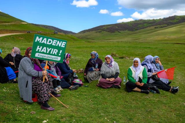 Protesters sit while a woman holds a placard reading “No to the mine” during a protest march against mining at the Aybasti Plateau in Ordu Province, northeastern Turkey, on May 8, 2026. With Turkey hosting COP31 in November 2026, its own environmental record is being scrutinised, with activists warning about the growing number of water-intensive mining projects as resources dry up. (Photo by Yasin AKGUL / AFP) / TO GO WITH AFP STORY by BURC?N GERCEK