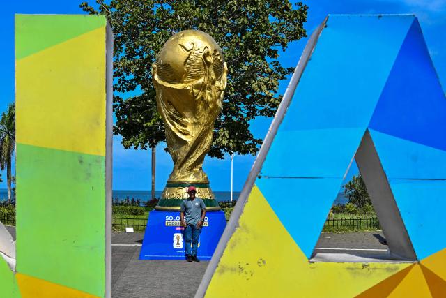 A man poses for a photo in front a giant replica of the FIFA World Cup trophy at the Cinta Costera in Panama City on May 13, 2026. Panama will play in the FIFA World Cup hosted by the United States, Mexico, and Canada from June 11 to July 19, 2026. (Photo by Martin BERNETTI / AFP)