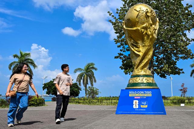 People walk past a giant replica of the FIFA World Cup trophy at the Cinta Costera in Panama City on May 13, 2026. Panama will play in the FIFA World Cup hosted by the United States, Mexico, and Canada from June 11 to July 19, 2026. (Photo by Martin BERNETTI / AFP)
