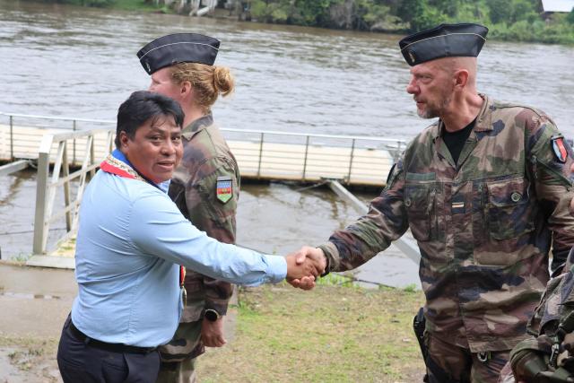 Mayor of Camopi Laurent Yawalou (L) welcomes French Air Division General Geraud Laborie (R) upon his arrival in Camopi, a town on the border with Brazil in the French overseas department of Guiana, on May 11, 2026, where residents are protesting against the increasingly frequent border crossings by illegal gold miners. (Photo by Guillaume REUGE / AFP)