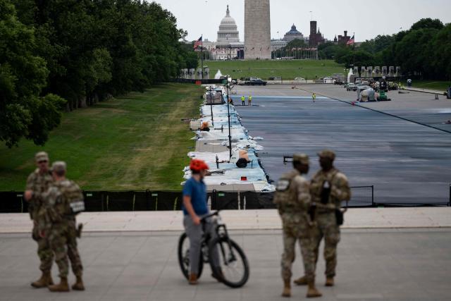 A cyclist is seen next to National Guard members near the Lincoln Memorial Reflecting Pool as it is being resurfaced in Washington, DC, on May 13, 2026. Workers have been resurfacing the bottom of Washington's famous Lincoln Memorial Reflecting Pool with "American flag blue"-colored material used in swimming pools, following an order by US President Donald Trump. (Photo by Kent Nishimura / AFP)