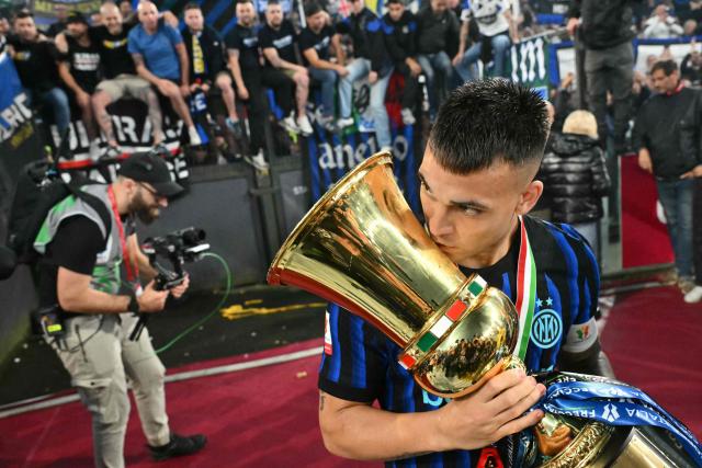 Inter Milan's Argentine forward #10 Lautaro Martinez kisses the trophy of the Italian Cup (Coppa Italia) as he celebrates with teammates and fans after Inter won the final football match between Lazio Rome and Inter Milan at the Olympic stadium in Rome on May 13, 2026. (Photo by Alberto PIZZOLI / AFP)