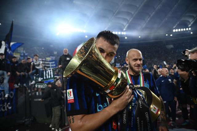 Inter Milan's Argentine forward #10 Lautaro Martinez kisses the trophy of the Italian Cup (Coppa Italia) as he celebrates with Inter Milan's Italian defender #32 Federico Dimarco, teammates and fans after Inter won the final football match between Lazio Rome and Inter Milan at the Olympic stadium in Rome on May 13, 2026. (Photo by Isabella BONOTTO / AFP)