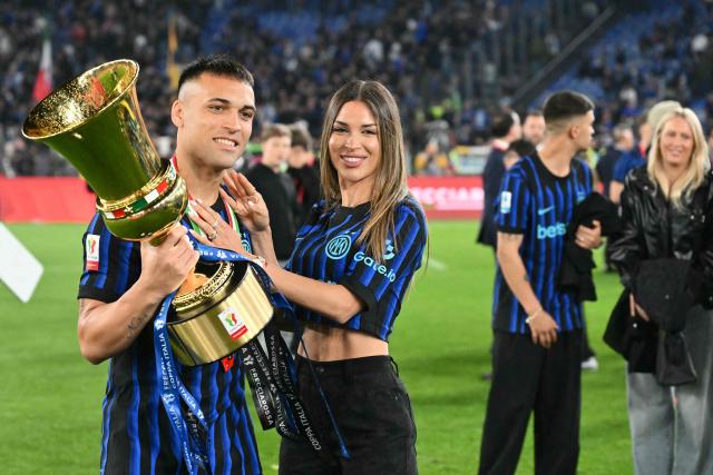 Inter Milan's Argentine forward #10 Lautaro Martinez holds the trophy of the Italian Cup (Coppa Italia) and poses with his wife Agustina Gandolfo after Inter won the final football match between Lazio Rome and Inter Milan at the Olympic stadium in Rome on May 13, 2026. (Photo by Alberto PIZZOLI / AFP)