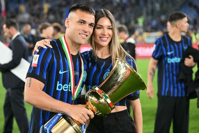 Inter Milan's Argentine forward #10 Lautaro Martinez holds the trophy of the Italian Cup (Coppa Italia) and poses with his wife Agustina Gandolfo after Inter won the final football match between Lazio Rome and Inter Milan at the Olympic stadium in Rome on May 13, 2026. (Photo by Alberto PIZZOLI / AFP)