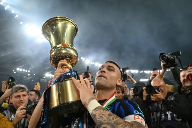 Inter Milan's Argentine forward #10 Lautaro Martinez lifts the trophy of the Italian Cup (Coppa Italia) and celebrates with teammates and fans after Inter won the final football match between Lazio Rome and Inter Milan at the Olympic stadium in Rome on May 13, 2026. (Photo by Alberto PIZZOLI / AFP)