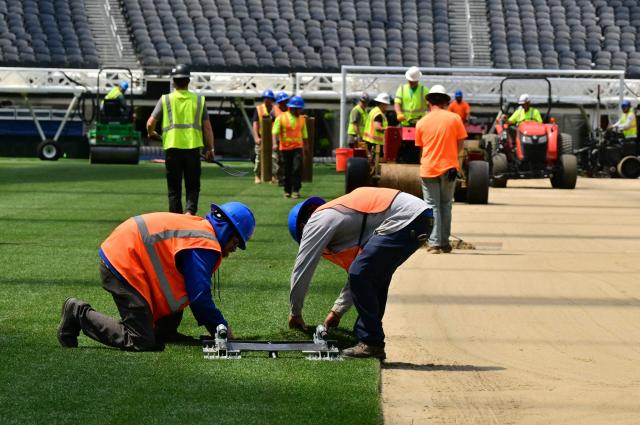 Workers install turf on the pitch at SoFi Stadium in Inglewood, California, ahead of its temporary renaming to Los Angeles Stadium for the World Cup on May 13, 2026. The US Men's National Team will play their first 2026 FIFA World Cup match on June 12 against Paraguay. (Photo by Frederic J. Brown / AFP)