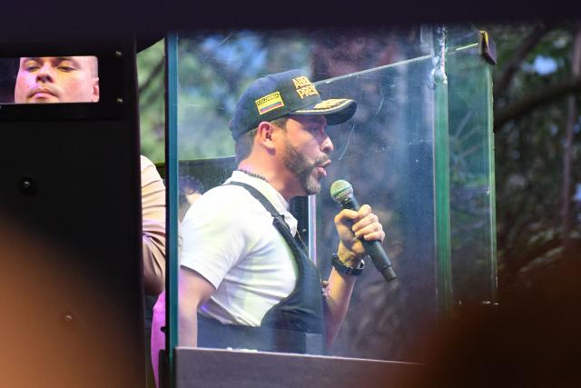 Supporters of Colombia's right-wing presidential candidate Abelardo de la Espriella, from the Defensores de la Patria movement, speaks behind a bulletproof glass during a campaign rally in Envigado, Antioquia department, Colombia on May 13, 2026. Colombia will hold presidential elections on May 31. (Photo by Jaime SALDARRIAGA / AFP)