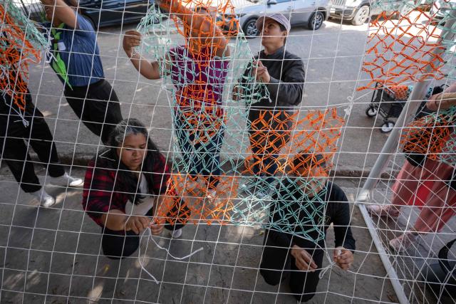 Migrants and advocates work on a football goal net as they rehearse the setup of Tejiendo Redes (Weaving Nets), an art project at Centro 32, a migrants support NGO, ahead of its presentation in Tijuana, Baja California, Mexico, on May 13, 2026. Conceived by Mexican artist Betsabee Romero, the project seeks to give visibility to migrants through art, using the FIFA World Cup as a platform. Finished goals with nets, all woven by migrants in Tijuana, Mexico, will be exhibited at the Mexico-US border before crossing into the United States. (Photo by Guillermo Arias / AFP)