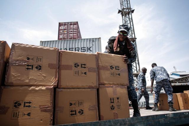 A member of the Transnational Organized Crime Unit (TOCU), a specialized unit of the Sierra Leone Police (SLP) dedicated to combating drug trafficking, organized crime and cross-border criminal activities, loads boxes containing Tapentadadol (Tramadol) tablets and capsules into the back of a truck after seizing four 20 feet containers originating from India at the Freetown Terminal in Freetown, on March 27, 2026. In many regions of West Africa, tapentadol is still sold as tramadol, with even authorities using tramadol as a generic umbrella code for all pharmaceutical opioids. Tapentadol pills and capsules, a powerful synthetic opioid that Indian pharmaceutical companies have been exporting to the region in strengths not approved in India, not registered in the destination countries, and not authorised by any recognised international regulatory body. (Photo by Saidu BAH / AFP)