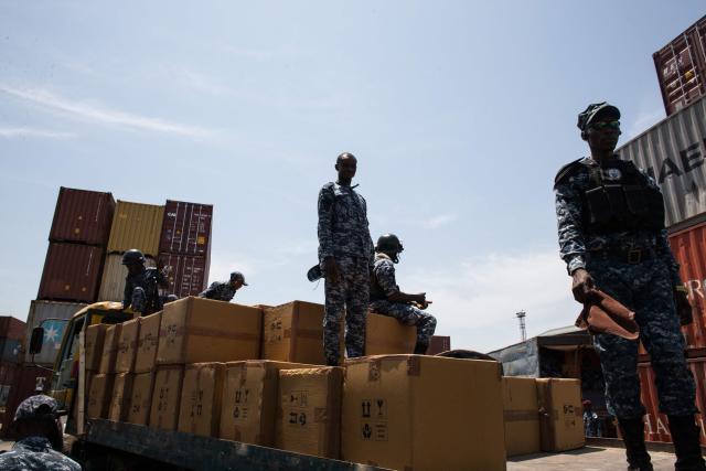Members of the Transnational Organized Crime Unit (TOCU), a specialized unit of the Sierra Leone Police (SLP) dedicated to combating drug trafficking, organized crime and cross-border criminal activities, guard boxes containing Tapentadadol (Tramadol) tablets and capsules after seizing four 20 feet containers originating from India at the Freetown Terminal in Freetown, on March 27, 2026. In many regions of West Africa, tapentadol is still sold as tramadol, with even authorities using tramadol as a generic umbrella code for all pharmaceutical opioids. Tapentadol pills and capsules, a powerful synthetic opioid that Indian pharmaceutical companies have been exporting to the region in strengths not approved in India, not registered in the destination countries, and not authorised by any recognised international regulatory body. (Photo by Saidu BAH / AFP)