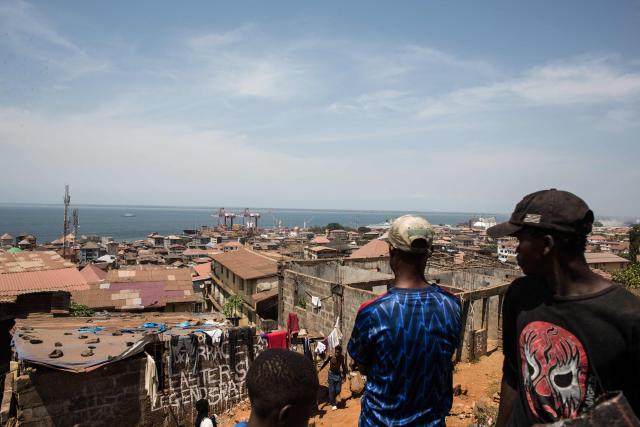 Residents look at the Freetown Terminal in Freetown, on March 27, 2026. In many regions of West Africa, tapentadol is still sold as tramadol, with even authorities using tramadol as a generic umbrella code for all pharmaceutical opioids. Tapentadol pills and capsules, a powerful synthetic opioid that Indian pharmaceutical companies have been exporting to the region in strengths not approved in India, not registered in the destination countries, and not authorised by any recognised international regulatory body. (Photo by Saidu BAH / AFP)