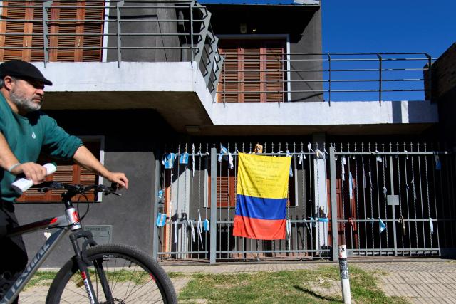 A man on a bicycle passes in front of a house displaying a Colombian flag bearing a message of thanks to Argentine footballer Lionel Messi in his childhood neighborhood in Rosario, Santa Fe province, Argentina, on April 30, 2026. At the age of 12, Lionel Messi ended the career of his first coach. When Enrique Dominguez stopped coaching him in 1999 at the youth club Malvinas Argentinas in the city of Rosario, he resigned, saying he had "already coached the best player in the world", who could now be set to play in his sixth World Cup. (Photo by Marcelo Manera / AFP)