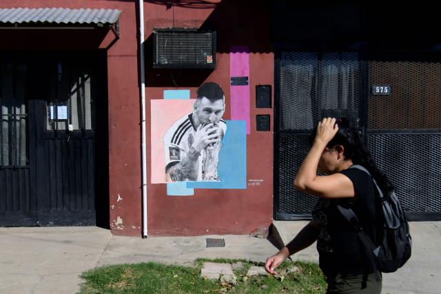 A woman walks past a mural of Argentine footballer Lionel Messi in his childhood neighborhood in Rosario, Santa Fe province, Argentina, on April 30, 2026. At the age of 12, Lionel Messi ended the career of his first coach. When Enrique Dominguez stopped coaching him in 1999 at the youth club Malvinas Argentinas in the city of Rosario, he resigned, saying he had "already coached the best player in the world", who could now be set to play in his sixth World Cup. (Photo by Marcelo Manera / AFP)