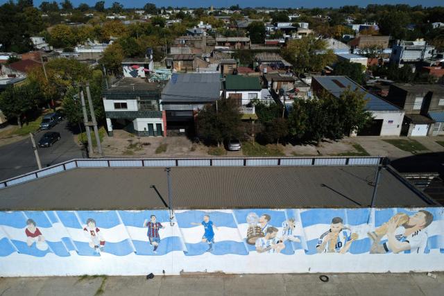 An aerial view shows a mural depicting different stages of the career of Argentine footballer Lionel Messi in Rosario, Santa Fe province, Argentina, on April 30, 2026. At the age of 12, Lionel Messi ended the career of his first coach. When Enrique Dominguez stopped coaching him in 1999 at the youth club Malvinas Argentinas in the city of Rosario, he resigned, saying he had "already coached the best player in the world", who could now be set to play in his sixth World Cup. (Photo by Marcelo Manera / AFP)