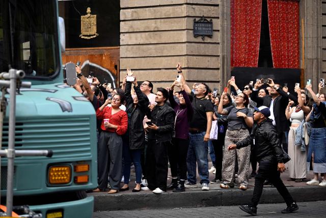 Fans of the Irish rock band U2 take photos during the second day of recording of its music video in downtown Mexico City on May 13, 2026. (Photo by Alfredo ESTRELLA / AFP)