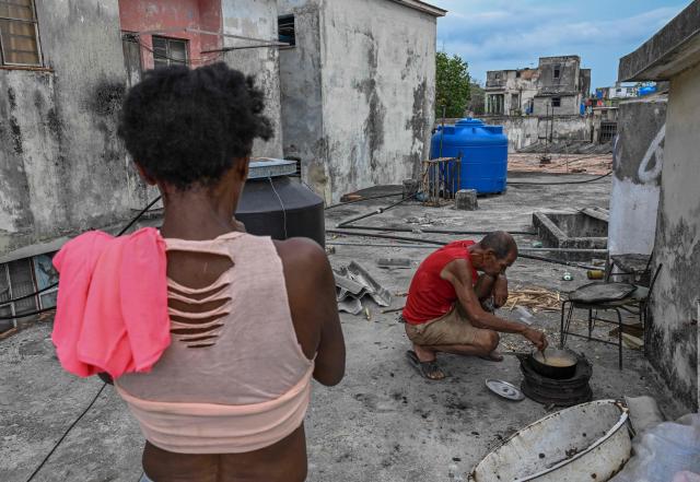 A man cooks with firewood during a blackout in Havana on May 13, 2026. Cuba blamed the United States for the "particularly tense" situation in its power grid on May 13, 2026, which has been plagued by prolonged blackouts, while Washington once again offered $100 million in aid to the island. (Photo by Yamil LAGE / AFP)