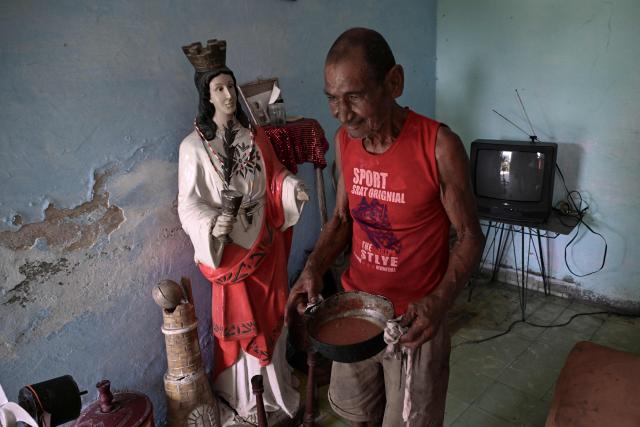 A man walks with a pot of food past a religious statue of Saint Barbara during a blackout in Havana on May 13, 2026. Cuba blamed the United States for the "particularly tense" situation in its power grid on May 13, 2026, which has been plagued by prolonged blackouts, while Washington once again offered $100 million in aid to the island. (Photo by Yamil LAGE / AFP)