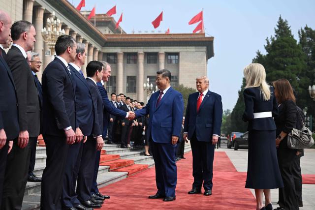 China's President Xi Jinping (C) shakes hands with members of the US delegation as US President Donald Trump (3rd R) looks on during a welcome ceremony at the Great Hall of the People in Beijing on May 14, 2026. (Photo by Kenny HOLSTON / POOL / AFP)