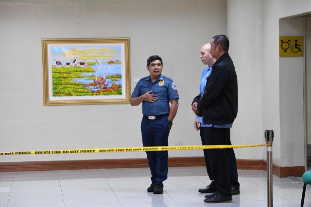 A policeman (R) talks to Senate security personnel near the site where gunshots were fired the night before inside the Senate building in Manila on May 14, 2026. Police said May 14 they detained a person in connection with gunfire the previous night inside the Philippine senate, where a lawmaker wanted by the International Criminal Court took refuge. (Photo by TED ALJIBE / AFP)