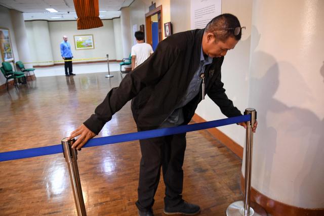 A Senate security installs a barrier near the site where gun shots were fired the night before inside the Senate building in Manila on May 14, 2026. Police said May 14 they detained a person in connection with gunfire the previous night inside the Philippine senate, where a lawmaker wanted by the International Criminal Court took refuge. (Photo by TED ALJIBE / AFP)