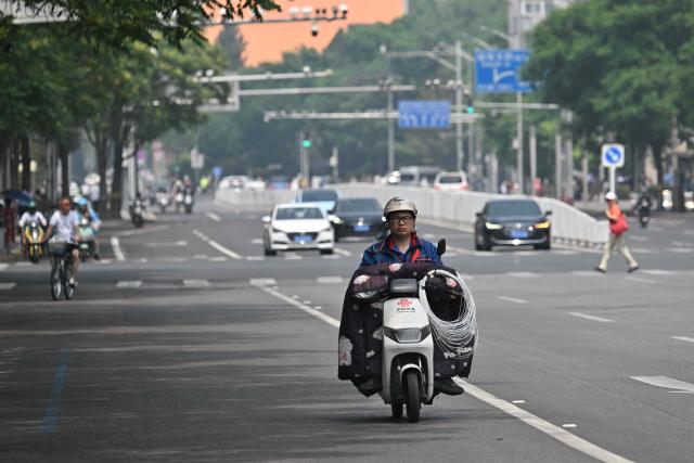 A man rides his motorcycle on a street in Beijing on May 14, 2026, amid a state visit by US President Donald Trump. (Photo by Hector RETAMAL / AFP)