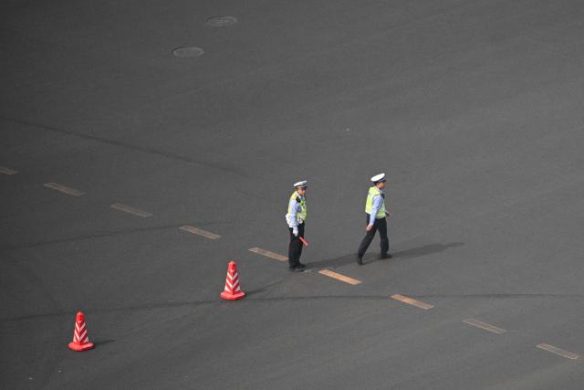 Traffic control officers are seen on a street in Beijing on May 14, 2026, amid a state visit by US President Donald Trump. (Photo by Hector RETAMAL / AFP)