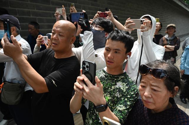 People gather to watch US President Donald Trump's motorcade pass by in Beijing on May 14, 2026. (Photo by GREG BAKER / AFP)