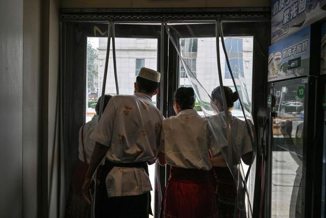 TOPSHOT - Workers in a mall try to watch US President Donald Trump's motorcade pass by in Beijing on May 14, 2026. (Photo by HECTOR RETAMAL / AFP)