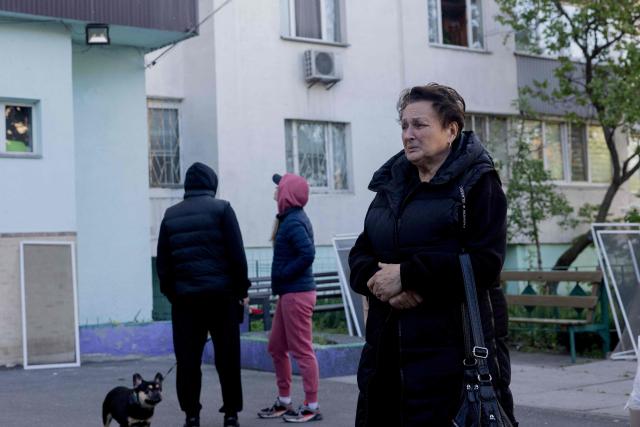 A local resident reacts near a residential building partially destroyed following Russian drone and missile strikes in Kyiv on May 14, 2026, amid the Russian invasion of Ukraine. Russia launched more than 670 drones and 56 missiles at Ukraine overnight, Ukraine's President announced on May 14, 2026. (Photo by Tetiana DZHAFAROVA / AFP)