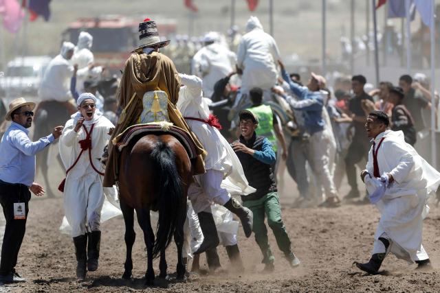 Men dressed in traditional attire celebrate with riders during a Tbourida, or Fantasia, equestrian performance in the city of Bouznika on May 13, 2026. (Photo by Abdel Majid BZIOUAT / AFP)