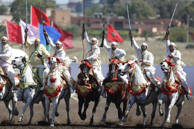 Men dressed in traditional attire ride horses and brandish their rifles during a Tbourida, or Fantasia, equestrian performance in the city of Bouznika on May 13, 2026. (Photo by Abdel Majid BZIOUAT / AFP)