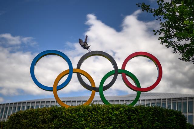 A crow flies above the Olympics Rings displayed at the headquarters of the International Olympic Committee (IOC) in Lausanne on May 13, 2026. (Photo by Fabrice COFFRINI / AFP)