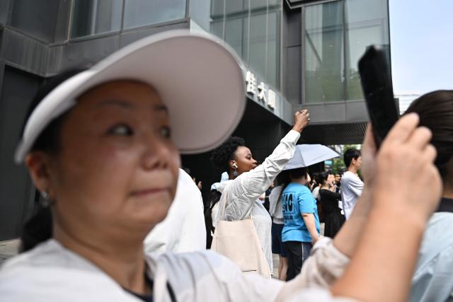 People gather to watch US President Donald Trump's motorcade in Beijing on May 14, 2026. (Photo by Pedro PARDO / AFP)
