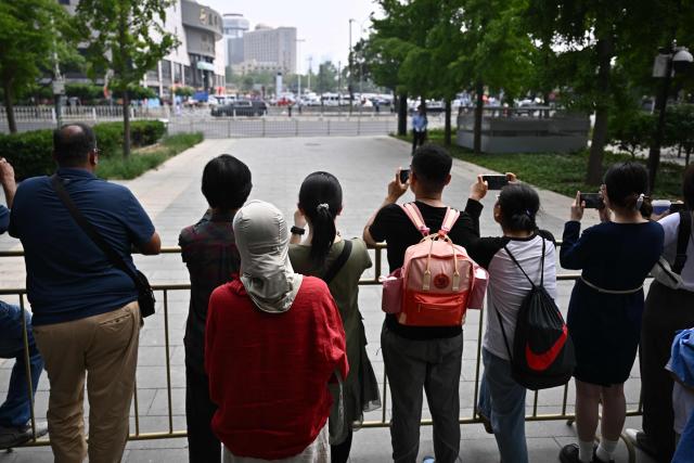 People gather to watch US President Donald Trump's motorcade in Beijing on May 14, 2026. (Photo by Pedro PARDO / AFP)
