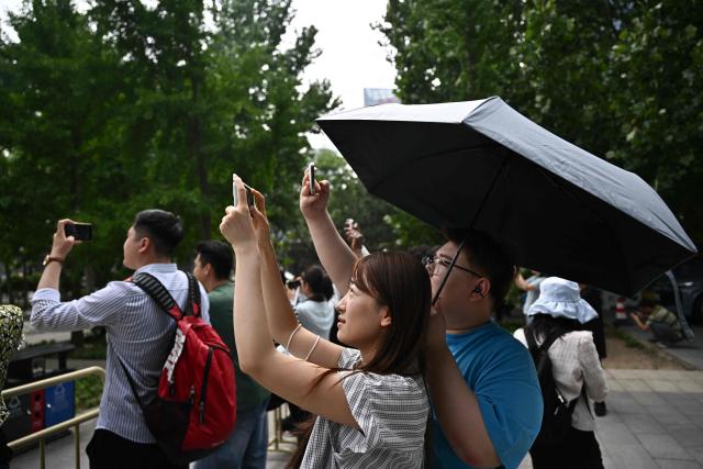 People gather to watch US President Donald Trump's motorcade in Beijing on May 14, 2026. (Photo by Pedro PARDO / AFP)
