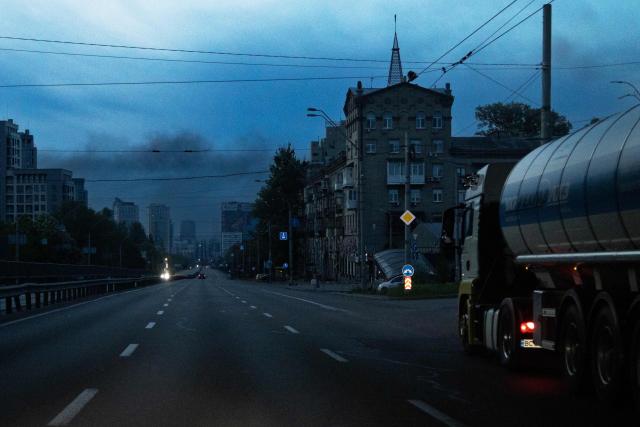 A truck is driven along the street as smoke rises above buildings in the background following an air attack in Kyiv on May 14, 2026, amid the Russian invasion of Ukraine. Large-scale Russian strikes on Kyiv killed one person and wounded at least 31 others, city authorities said on May 14, 2026, as Moscow ramped up attacks on Ukraine following a short-lived ceasefire. (Photo by Serhii Okunev / AFP)