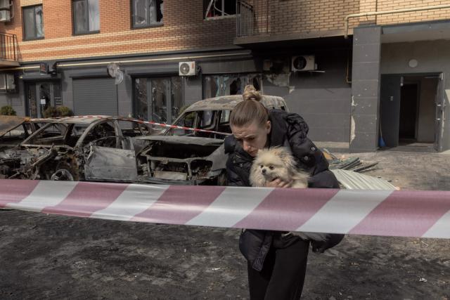 A woman with her dog leaves a damaged residential building following Russian drone and missile strikes in Kyiv on May 14, 2026, amid the Russian invasion of Ukraine. Ukraine's capital came under heavy aerial attack early on May 14, an AFP journalist reported, as Kyiv's mayor said Russia was striking the city. (Photo by Roman PILIPEY / AFP)