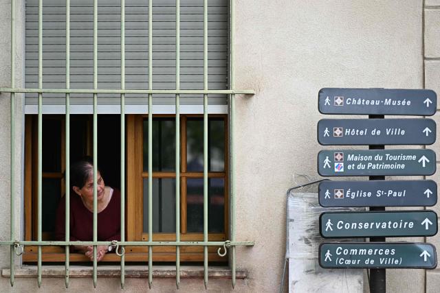 A woman looks at the street from a window ahead of the arrival of French far-right party Rassemblement National (RN) president Jordan Bardella for a visit in Beaucaire, southern France on May 14, 2026. (Photo by Gabriel BOUYS / AFP)