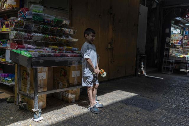 A Palestinian child stands with flowers in hand that were given to him by Israeli left-wing activists in the old city of Jerusalem ahead of Jerusalem day parade on May 14, 2026. Every year, thousands of Israeli nationalists, many of them religious Jews, march through Jerusalem and its annexed Old City, including in predominantly Palestinian neighbourhoods, waving Israeli flags, dancing and sometimes shouting inflammatory slogans. (Photo by ilia YEFIMOVICH / AFP)