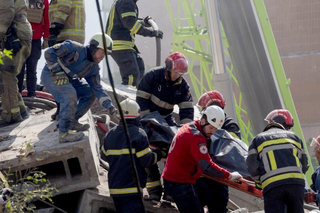 Rescuers carry a body at the site of a residential building following Russian drone and missile strikes in Kyiv on May 14, 2026, amid the Russian invasion of Ukraine. Ukraine's capital came under heavy aerial attack early on May 14, an AFP journalist reported, as Kyiv's mayor said Russia was striking the city. (Photo by Tetiana DZHAFAROVA / AFP)