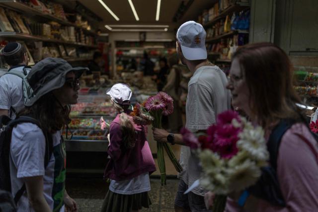Israeli left-wing activists walk with flowers in hand to give to the Palestinian population of the old city in Jerusalem ahead of Jerusalem day parade on May 14, 2026. Every year, thousands of Israeli nationalists, many of them religious Jews, march through Jerusalem and its annexed Old City, including in predominantly Palestinian neighbourhoods, waving Israeli flags, dancing and sometimes shouting inflammatory slogans. (Photo by ilia YEFIMOVICH / AFP)