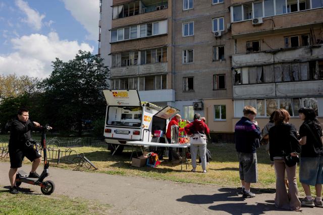 Volunteers distribute food to local residents near a partially destroyed residential building, following Russian drone and missile strikes in Kyiv on May 14, 2026, amid the Russian invasion of Ukraine. Ukraine's capital came under heavy aerial attack early on May 14, an AFP journalist reported, as Kyiv's mayor said Russia was striking the city. (Photo by Tetiana DZHAFAROVA / AFP)