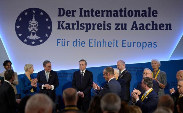 The former President of the European Central Bank (ECB) and former Italian Prime Minister Mario Draghi (C) is applauded by German Chancellor Friedrich Merz (C-R), Belarusian street protest leader Maria Kolesnikova (2nd L), the former leader of the conservative Christian Democratic Union (CDU) party Armin Laschet (3rd L), European Central Bank (ECB) President Christine Lagarde (R) and others as he is awarded the 2026 International Charlemagne Prize of Aachen, on May 14, 2026 in Aachen, western Germany. (Photo by Sascha Schuermann / AFP)