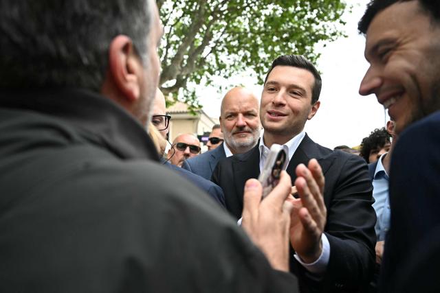French far-right party Rassemblement National (RN) president Jordan Bardella speaks with a local resident during a visit in Beaucaire, southern France on May 14, 2026. (Photo by Gabriel BOUYS / AFP)
