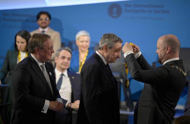 The former leader of the conservative Christian Democratic Union (CDU) party Armin Laschet (L) looks on as the former President of the European Central Bank (ECB) and former Italian Prime Minister Mario Draghi (C) is awarded with the 2026 International Charlemagne Prize of Aachen by Aachen's mayor Michael Ziemons (R) and on May 14, 2026 in Aachen, western Germany. (Photo by Sascha Schuermann / AFP)