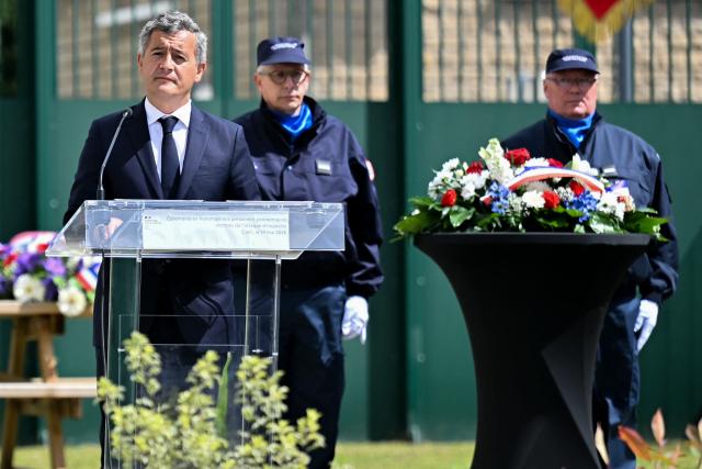 France's Justice Minister Gerald Darmanin (L) delivers a speech as he takes part in a visit marking the second anniversary of the 2024 Incarville attack, at the Pole de Rattachement dExtractions Judiciaires - PREJ (Judicial Extraction Coordination Centre) in Caen, north-western France on May 14, 2026. On May 14, 2024, a group of gunmen killed two prison officers and wounded three others, in an attack of a prison van transporting inmate Mohamed Amra at a motorway toll in Incarville, northern France. Amra's deadly escape marked a "turning point" in France, speeding up the introduction of new investigative tools and the construction of new prisons. However, investigators still face challenges in the face of a rapidly growing organised crime scene. (Photo by LOU BENOIST / AFP)
